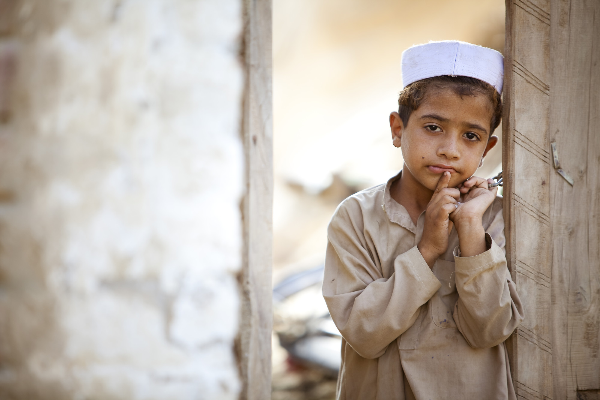 <p>
	A boy leans against the door of his ramshackle home.</p>