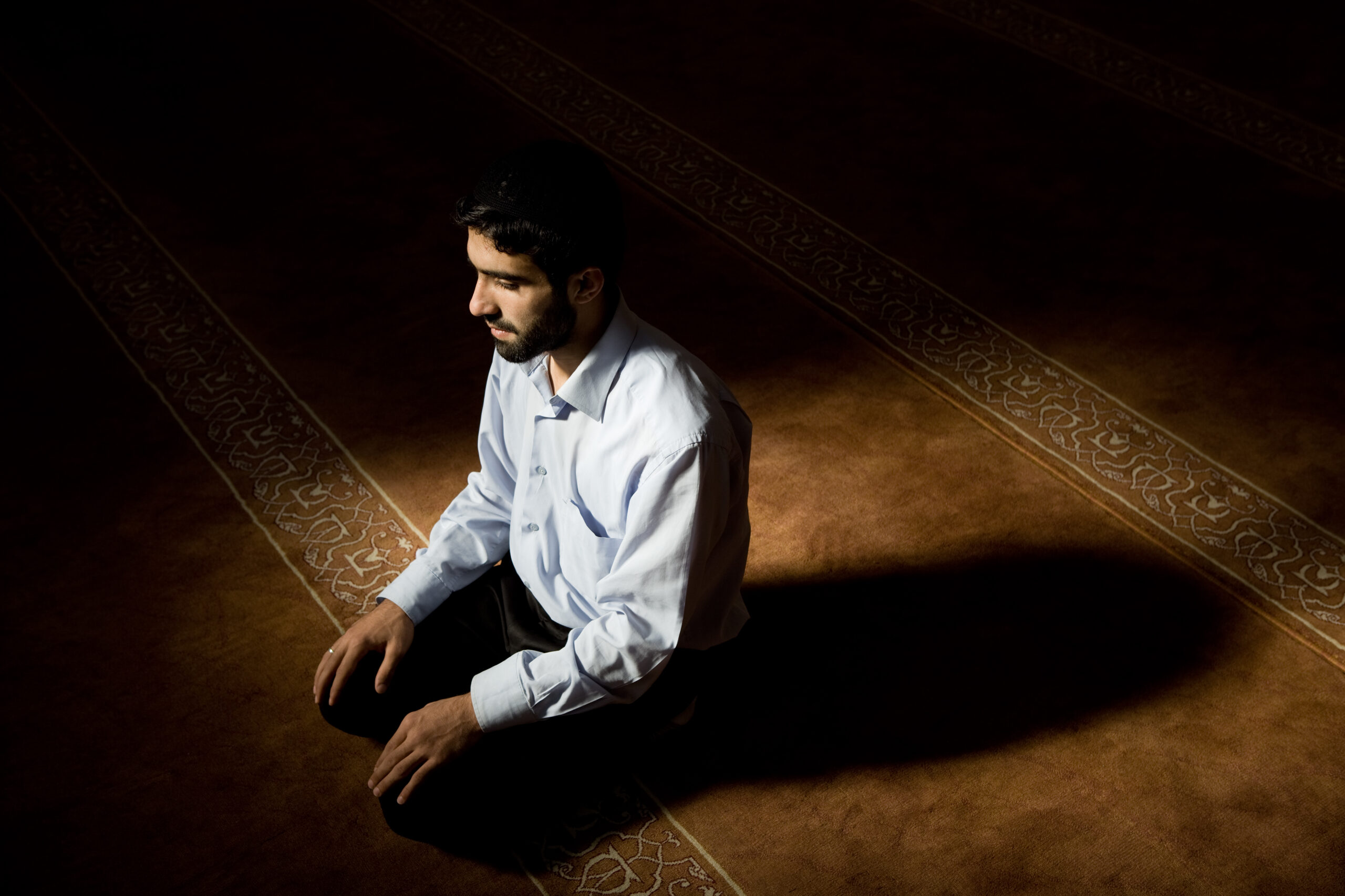 Young muslim man praying in mosque
