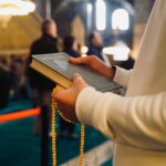 A person holding a Quran and prayer beads inside a mosque in Istanbul, Türkiye.