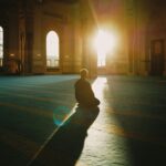 A person praying in a sunlit mosque in Malaysia, capturing tranquility and spirituality.