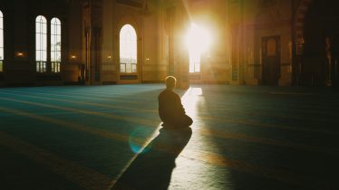 A person praying in a sunlit mosque in Malaysia, capturing tranquility and spirituality.
