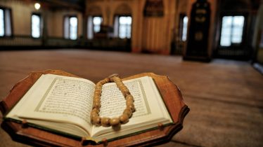 Open Quran with prayer beads in a historic Travnik mosque, symbolizing Islamic faith.